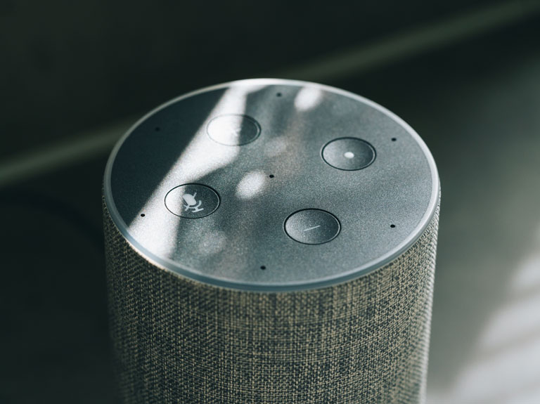The top of an Alexa speaker with four buttons: stop, start, volume up and volume down.