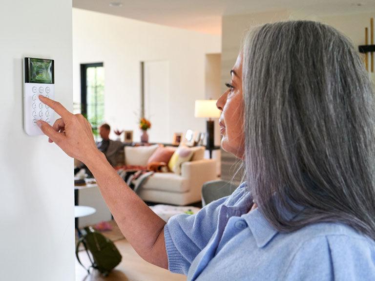 A woman uses her smart home security system